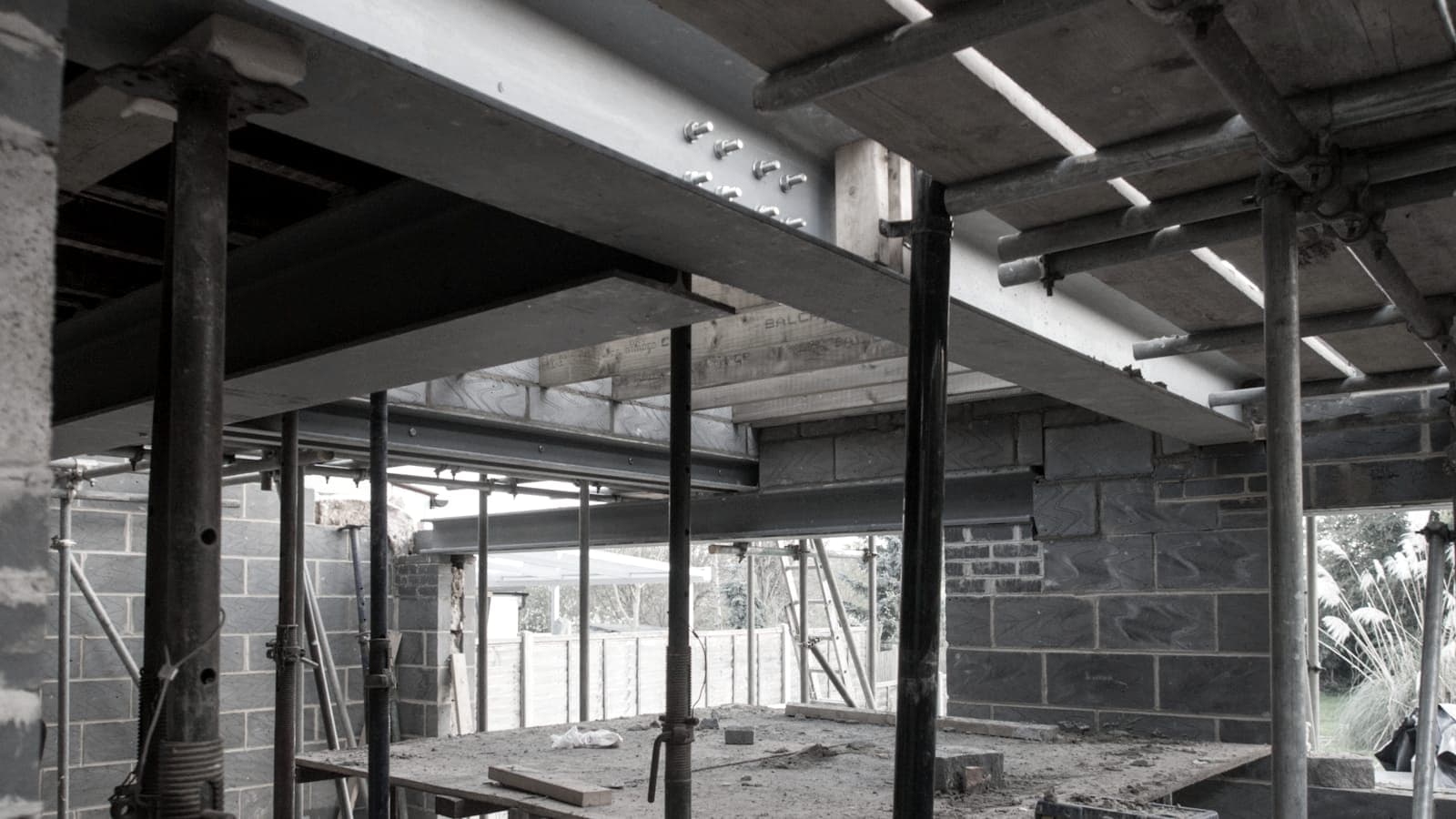Steel beams and adjustable props supporting a floor over a blockwork wall